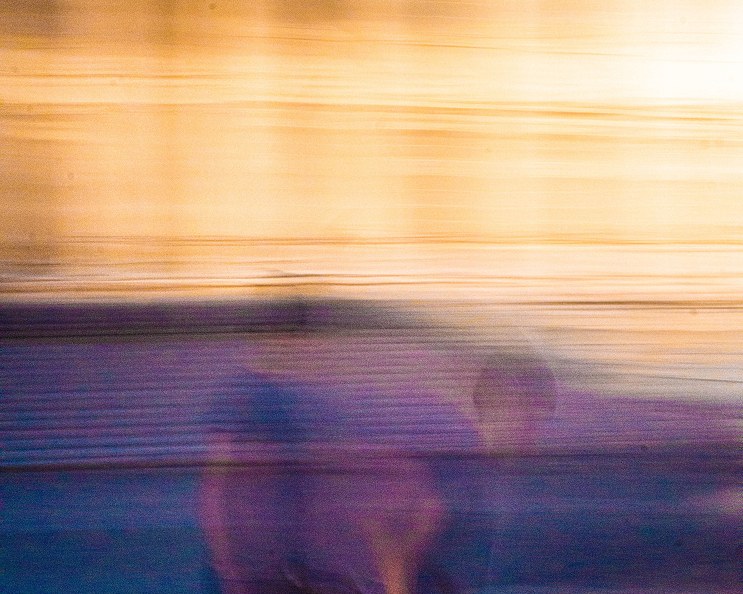 Two figures streaked into amber and violet light by a long exposure